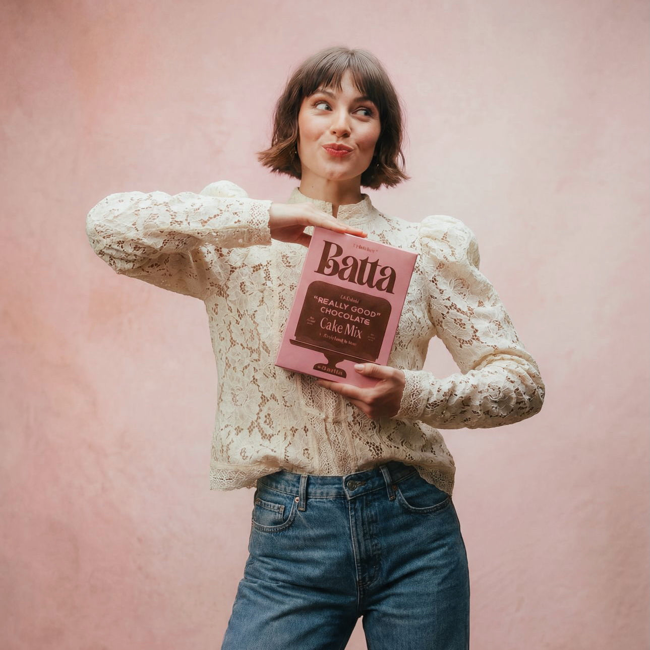 Woman holding a pink 'Batta' cake mix box against a pink background