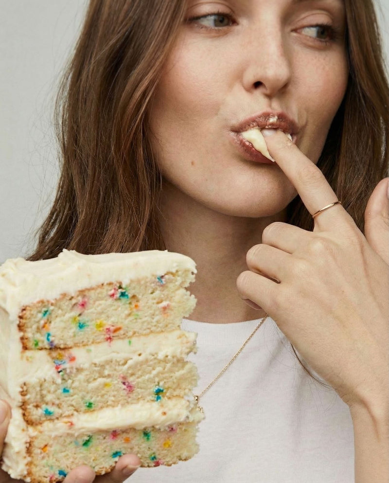 Woman eating a slice of cake with colorful sprinkles. Batta all-natural cake and frosting mixes - gourmet gifts for bakers, moms, foodies