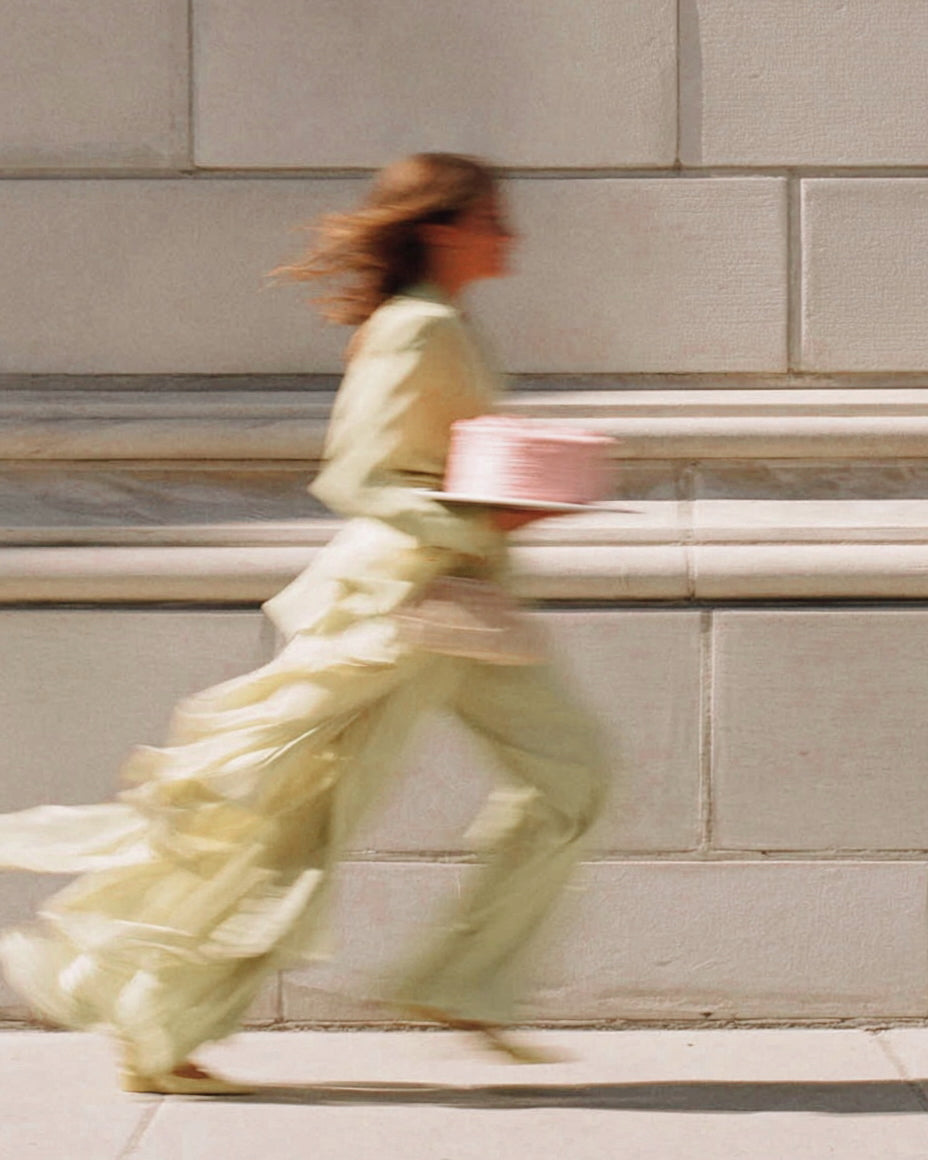 Person in a light green dress running past a stone wall. Batta all-natural cake and frosting mixes - gourmet gifts for bakers, moms, foodies